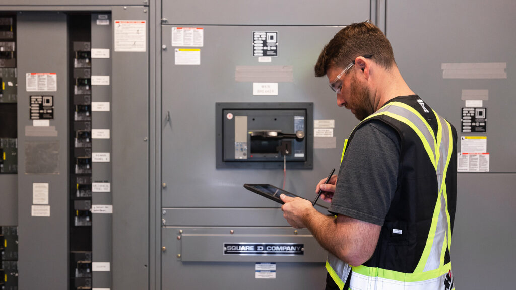 Houle electrician working in front of an electrical system with an annual operating permit